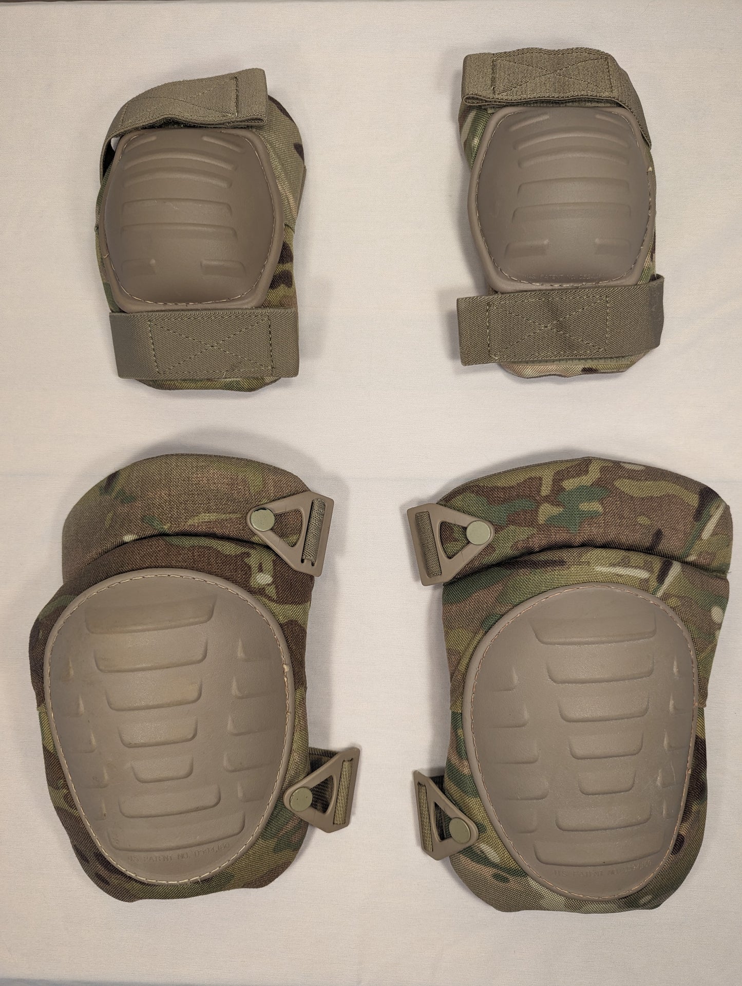 A complete set of U.S. Military tactical protective pads in OCP/Multicam camouflage, consisting of two elbow pads and two knee pads with tan hard plastic shells, laid out on a white background.