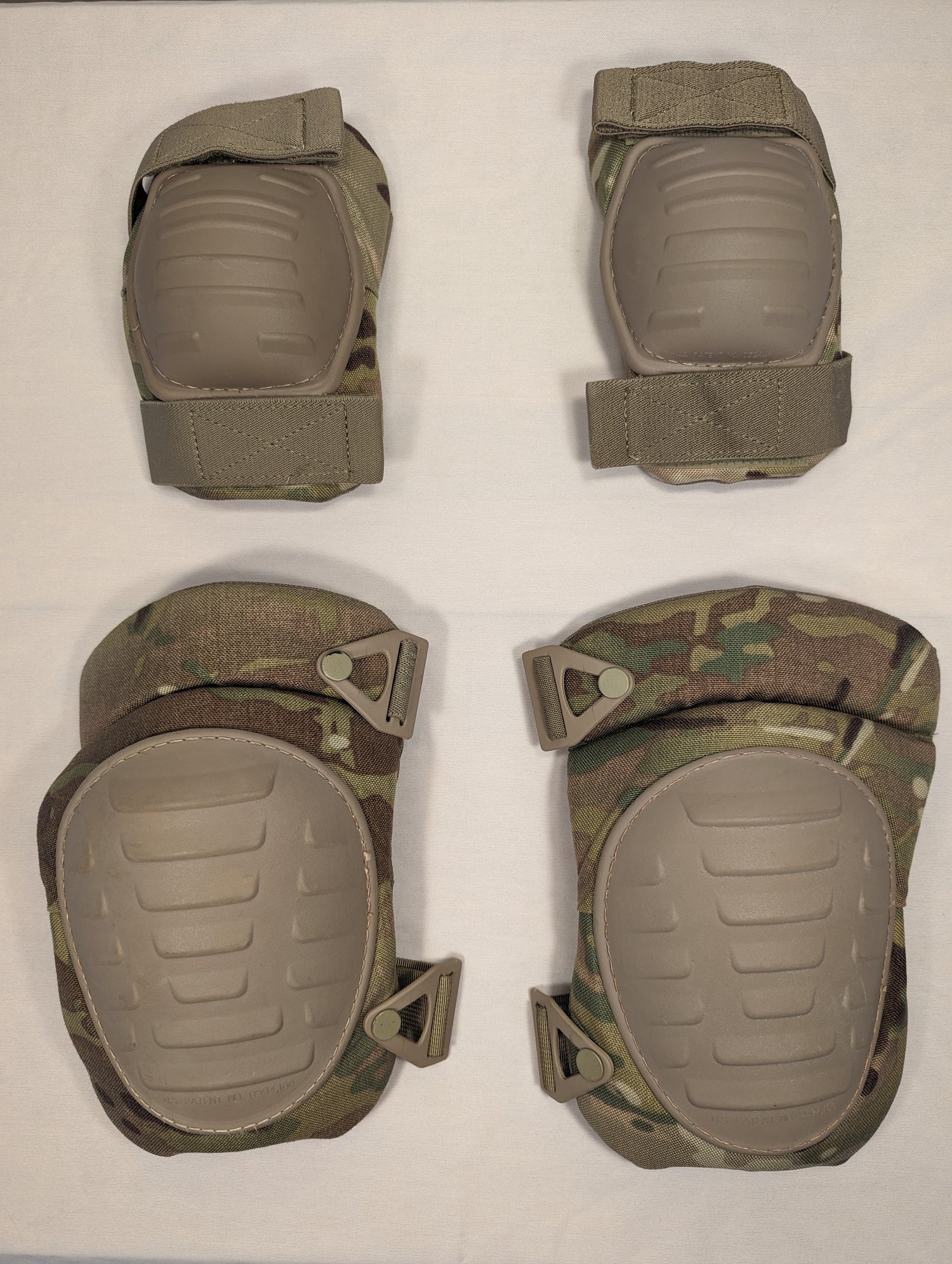 A complete set of U.S. Military tactical protective pads in OCP/Multicam camouflage, consisting of two elbow pads and two knee pads with tan hard plastic shells, laid out on a white background.