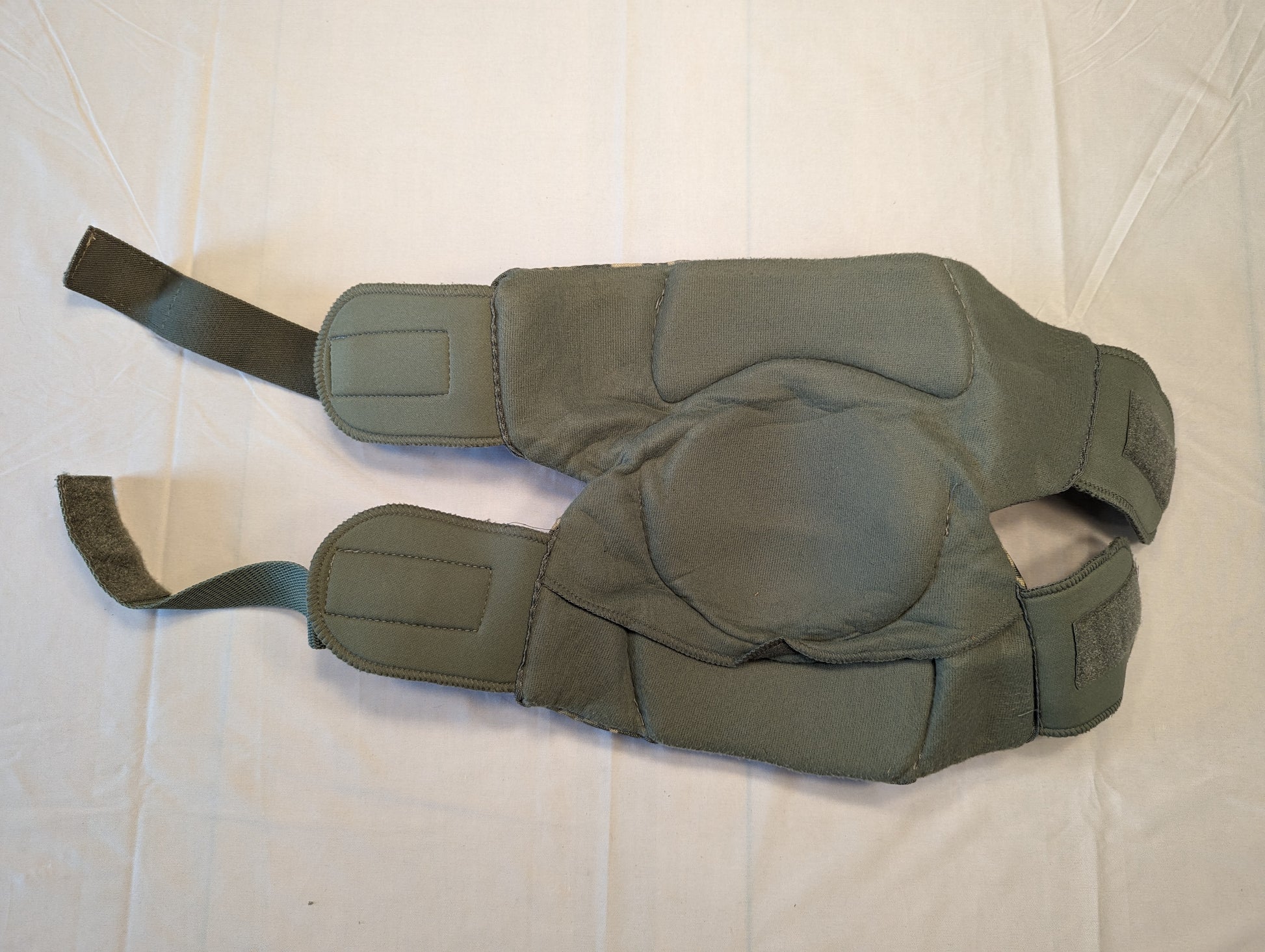 A pair of U.S. Military tactical knee pads in foliage green, laid flat on a white background, featuring hard plastic protective shells and adjustable hook-and-loop straps.