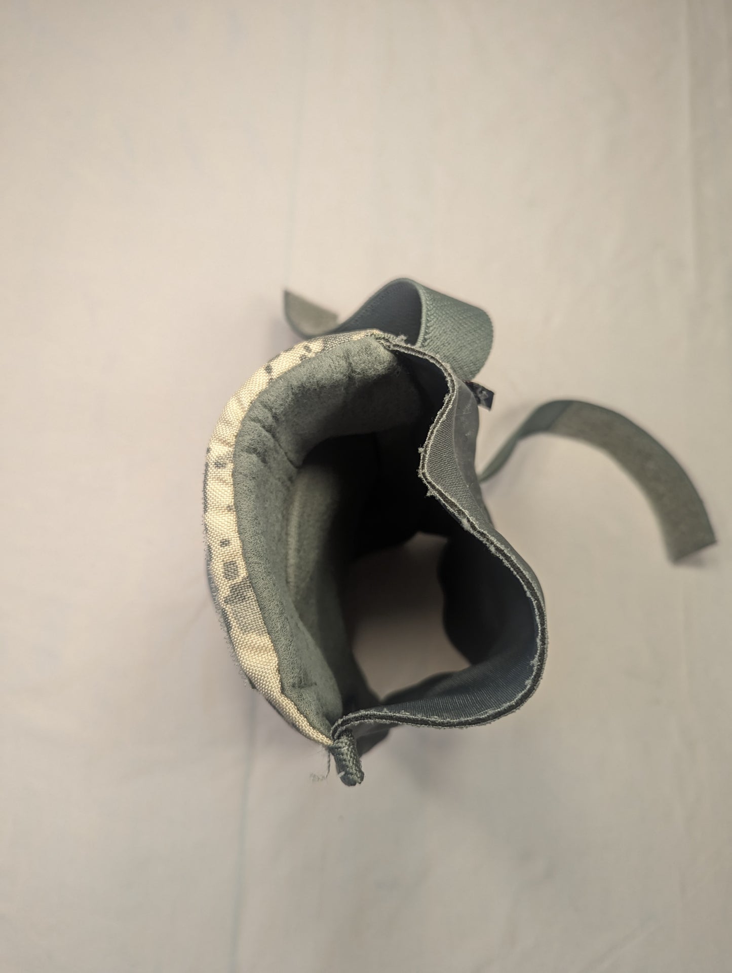 A close-up view looking into the open sleeve of a U.S. Military tactical knee or elbow pad, showing the ACU digital camouflage exterior and the thick, dark padded interior lining.