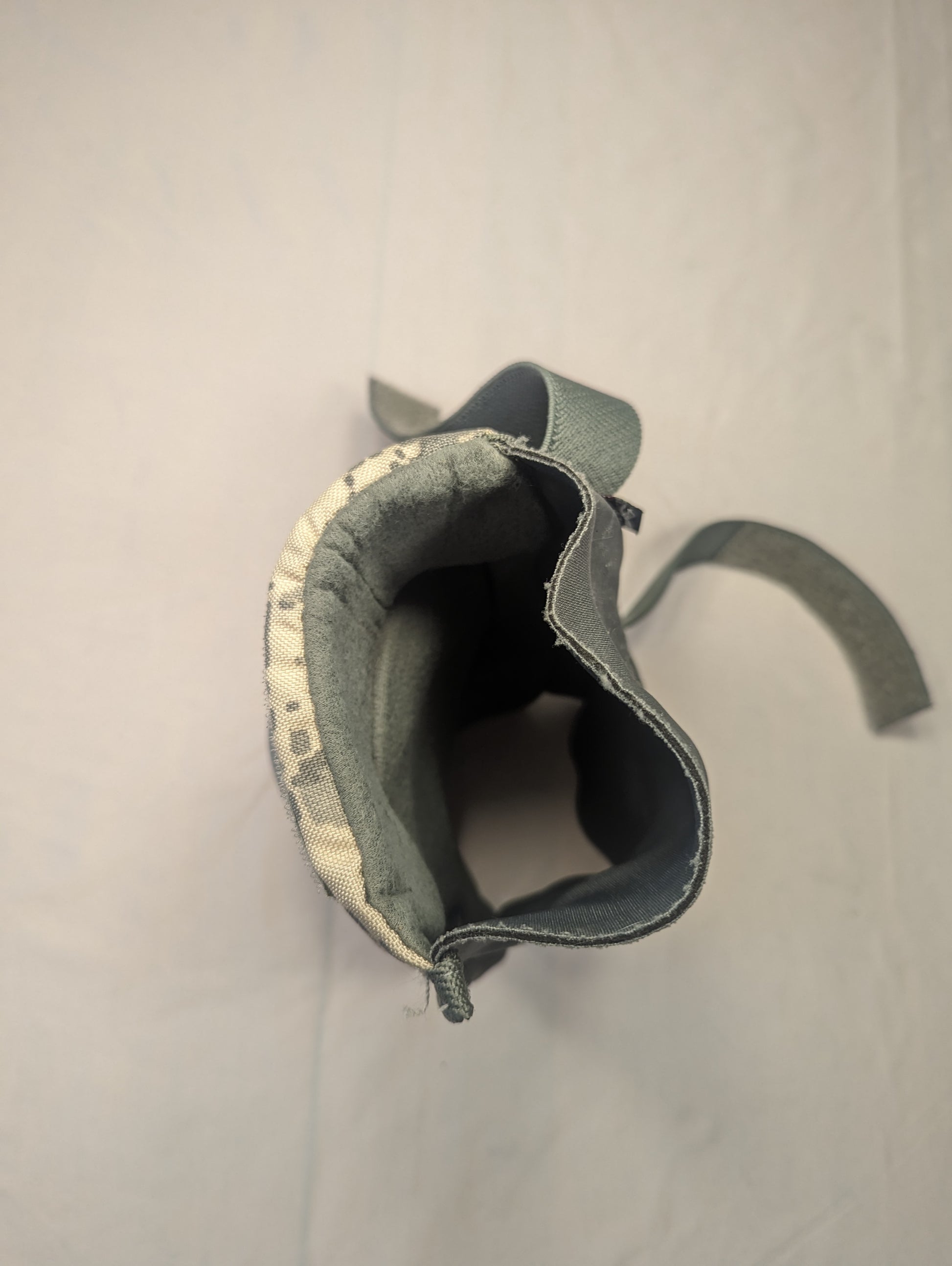 A close-up view looking into the open sleeve of a U.S. Military tactical knee or elbow pad, showing the ACU digital camouflage exterior and the thick, dark padded interior lining.