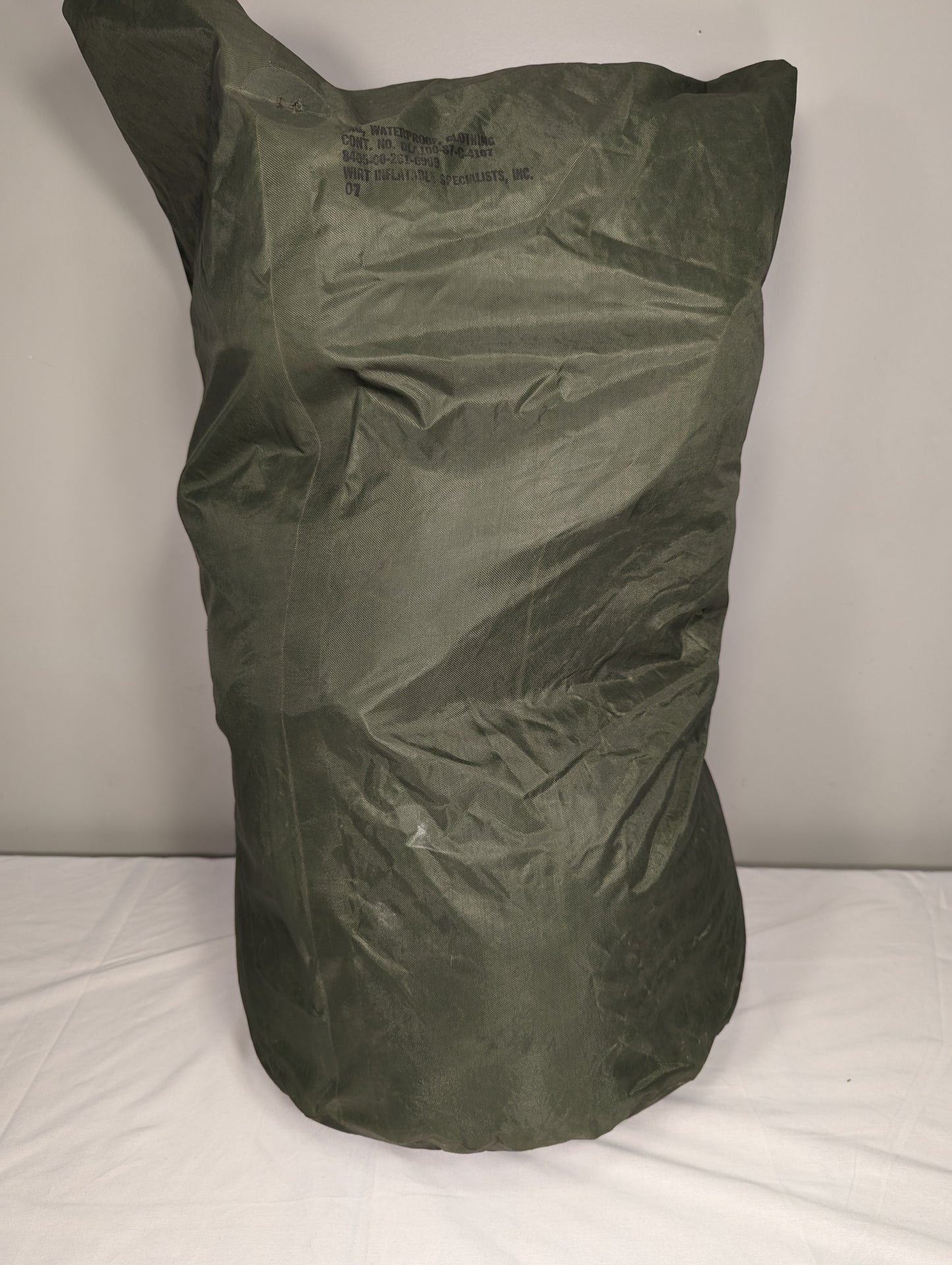 A large, stuffed U.S. Military Waterproof Clothing Bag in olive green, standing upright, displaying the wrinkled ripstop nylon texture and cinched top closure.
