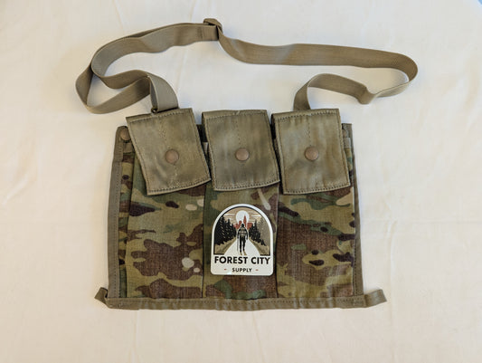 A U.S. Military Surplus OCP/Multicam Bandoleer laid flat, featuring three snap-button magazine pockets, a khaki strap, and a prominent 'FOREST CITY SUPPLY' logo sticker on the front.