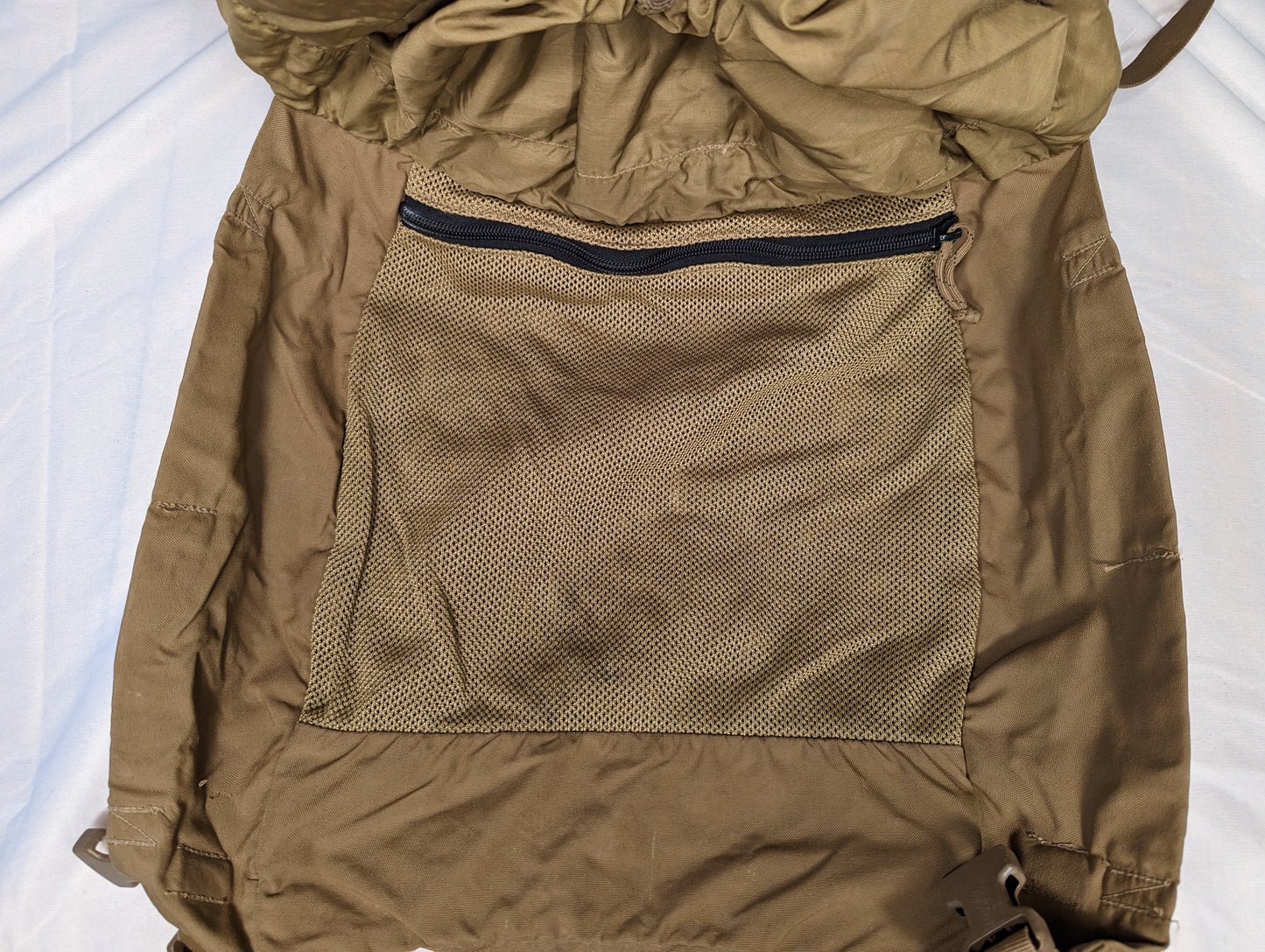 A close-up view of the internal zippered mesh pocket inside the main compartment of a U.S. Military Surplus USMC FILBE Rucksack in Coyote Brown, designed for organizing small gear.