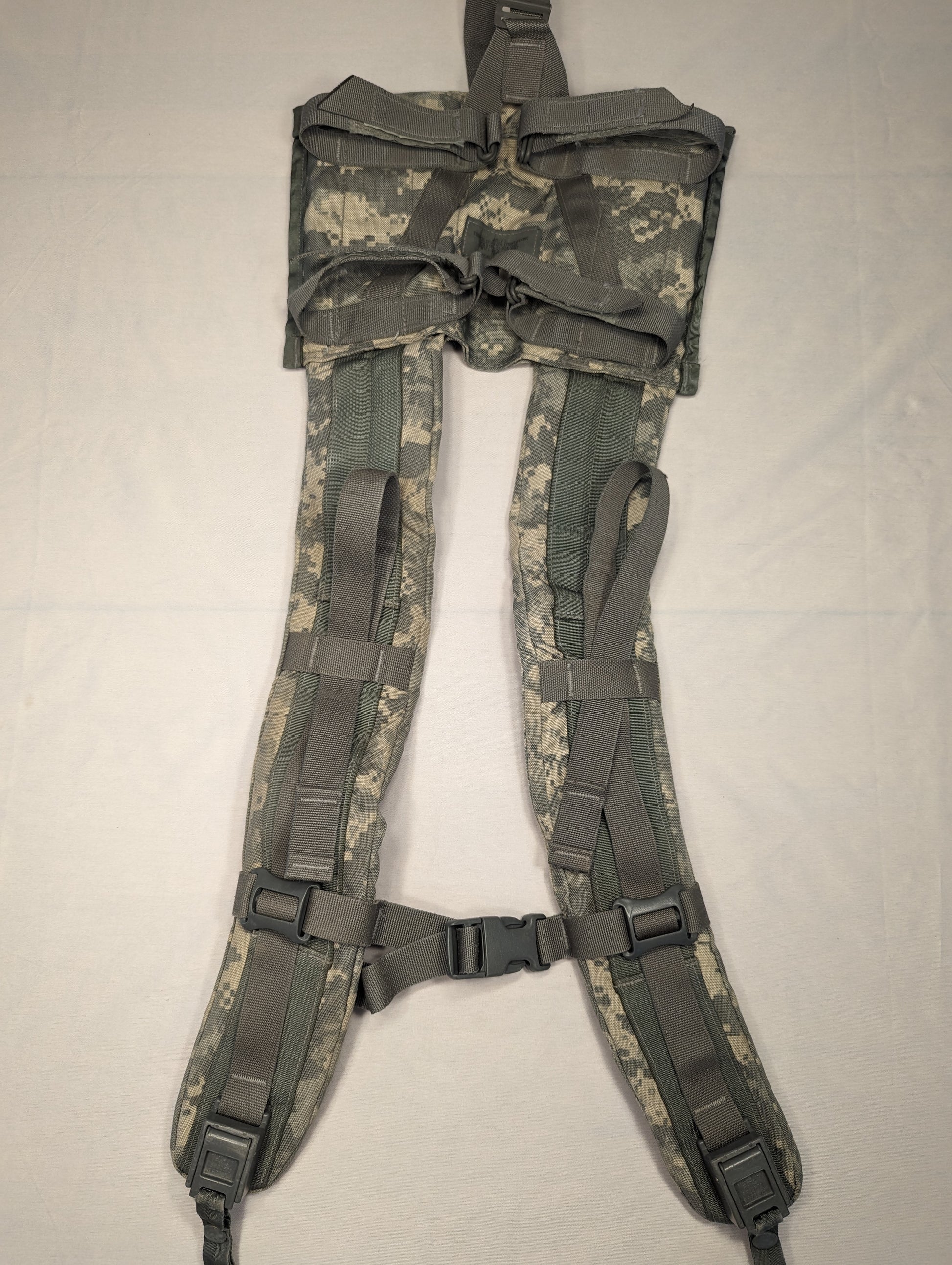 A close-up view of a U.S. Military Surplus Enhanced Frame Shoulder Straps assembly in ACU digital camouflage, laid flat, showing the padded construction, top yoke, and black plastic adjustment buckles.